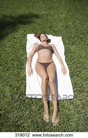 Young woman sunbathing on grass View Large Photo Image Stock Image - Young woman sunbathing on grass. Fotosearch