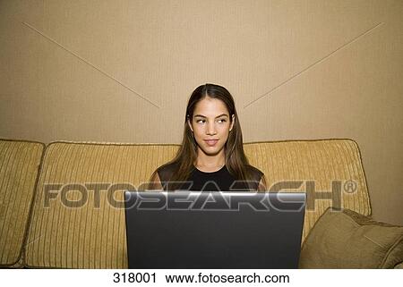 Young woman using laptop and sitting on sofa View Large Photo Image Stock Image - Young woman using laptop and sitting on sofa. Fotosearch