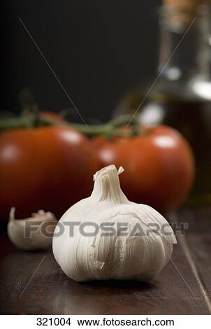 Picture - Bulb of garlic and vine tomatoes on wooden table. Fotosearch