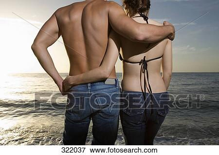 Couple embracing on beach at sunset View Large Photo Image Stock Photo - Couple embracing on beach at sunset. Fotosearch