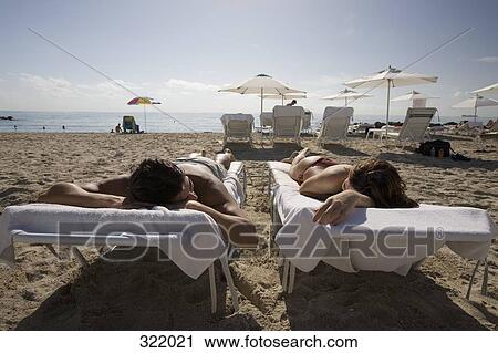Couple sunbathing on the beach View Large Photo Image Stock Image - Couple sunbathing on the beach. Fotosearch