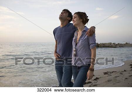 Couple walking along beach together and laughing View Large Photo Image Picture - Couple walking along beach together and laughing. Fotosearch