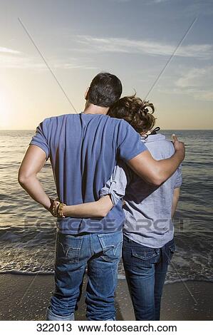 Man and woman standing looking at sunset together View Large Photo Image Stock Image - Man and woman standing looking at sunset together. Fotosearch