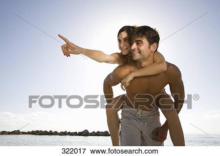 Man giving woman a piggyback by sea View Large Photo Image Stock Photo - Man giving woman a piggyback by sea. Fotosearch