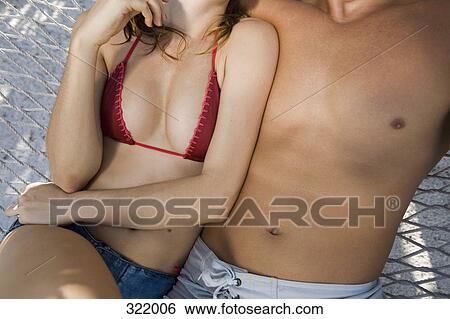 Stock Photograph - Midsection of couple sitting together in hammock. Fotosearch