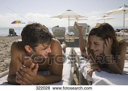 Young couple lying on deck chairs at beach View Large Photo Image Stock Photo - Young couple lying on deck chairs at beach. Fotosearch