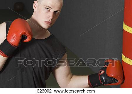 Stock Image - Male boxer hitting a punching bag. Fotosearch