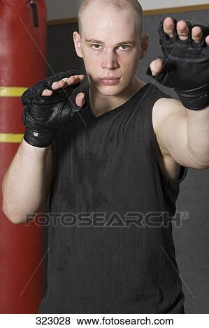 Stock Photo - Young man standing in gym with hands raised. Fotosearch