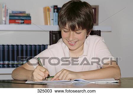 Boy sitting at table doing homework View Large Photo Image Stock Image - Boy sitting at table doing homework. Fotosearch