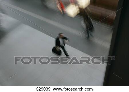 Commuter walking along platform at train station View Large Photo Image Stock Photo - Commuter walking along platform at train station. Fotosearch