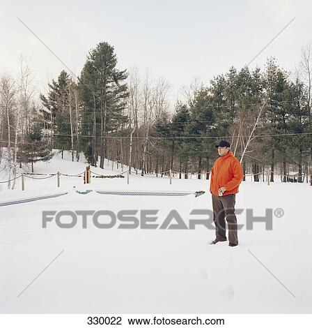 Man standing in snow with can in hand View Large Photo Image Stock Image - Man standing in snow with can in hand. Fotosearch