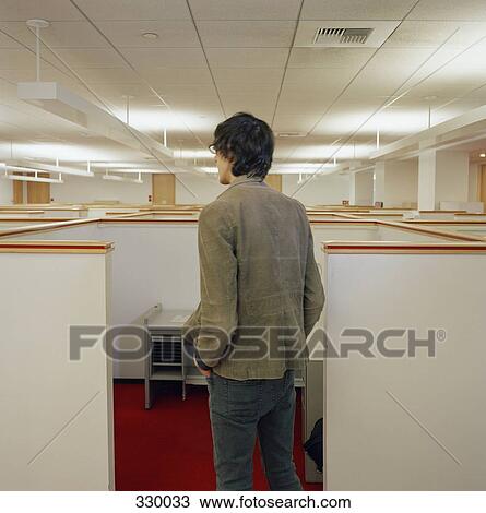 Stock Image - Young man looking over empty office cubicles. Fotosearch