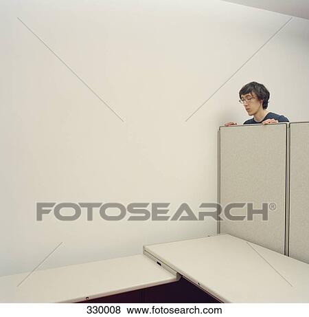 Young man looking over partition wall in empty cubicle View Large Photo Image Stock Photo - Young man looking over partition wall in empty cubicle. Fotosearch