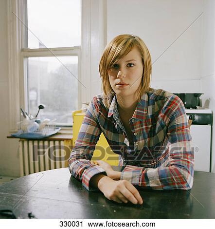 Young woman sitting at table in kitchen View Large Photo Image Stock Image - Young woman sitting at table in kitchen. Fotosearch