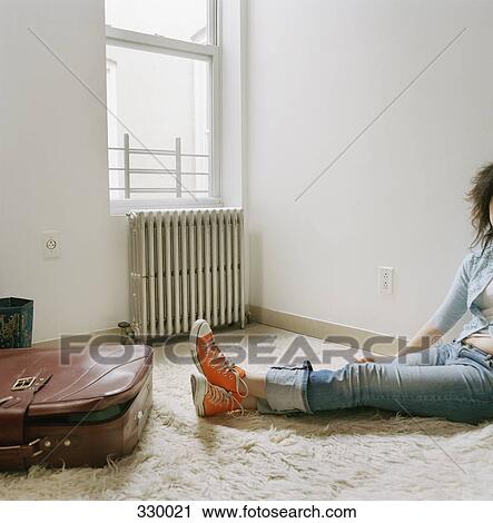 Young woman sitting on a rug with a suitcase at her feet View Large Photo Image Stock Image - Young woman sitting on a rug with a suitcase at her feet. Fotosearch