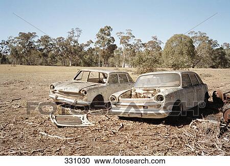 Stock Image - Two abandoned cars in a field. Fotosearch
