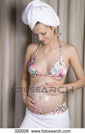 Pregnant woman rubbing moisturizer into her belly View Large Photo Image Stock Photograph - Pregnant woman rubbing moisturizer into her belly. Fotosearch