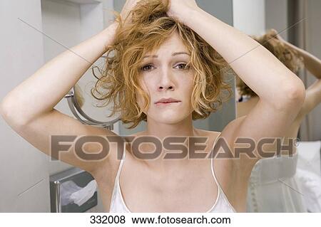 Stock Photo - Woman in bathroom tearing her hair out. Fotosearch