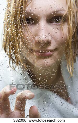Stock Photograph - Woman looking anxious through glass of shower. Fotosearch