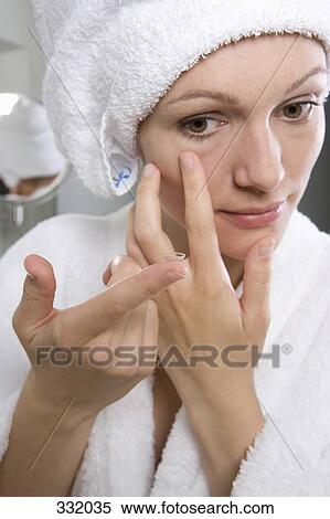 Woman putting in contact lens in bathroom View Large Photo Image Stock Photography - Woman putting in contact lens in bathroom. Fotosearch