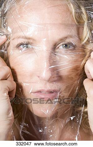 Woman stretching transparent sheet across her face View Large Photo Image Stock Photo - Woman stretching transparent sheet across her face. Fotosearch