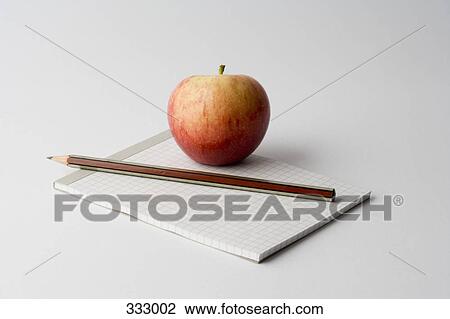 Stock Image - Apple and pencil on top of note pad. Fotosearch