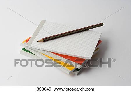Stock Photo - Pencil on top of stack of note pads. Fotosearch