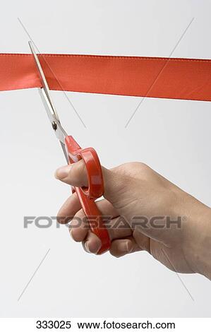 Stock Photography - Person cutting red ribbon with scissors. Fotosearch
