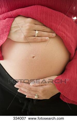 Stock Photo - Pregnant woman holding her abdomen. Fotosearch