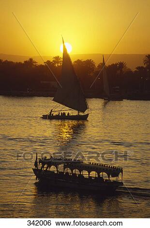 Sailing boat and water taxi floating on water at sunset, Luxor, Egypt View Large Photo Image Stock Photograph - Sailing boat and water taxi floating on water at sunset, Luxor, Egypt. Fotosearch