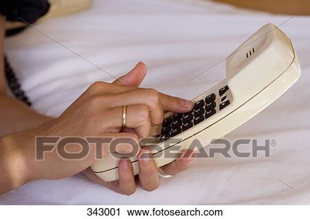 Stock Image - Woman dialing number on telephone receiver. Fotosearch