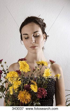 Young woman looking at bunch of flowers View Large Photo Image Stock Photo - Young woman looking at bunch of flowers. Fotosearch