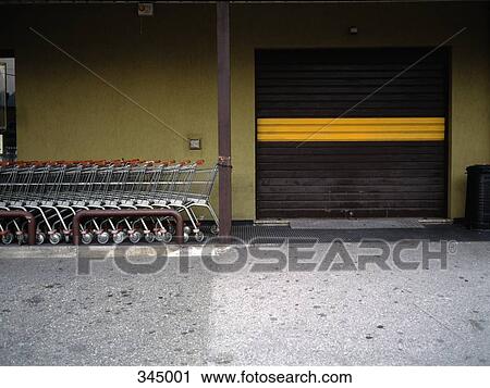 Stock Image - Shopping carts next to industrial door. Fotosearch