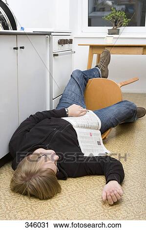 Young man lying on the ground with magazine after falling back in a chair View Large Photo Image Stock Image - Young man lying on the ground with magazine after falling back in a chair. Fotosearch