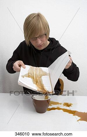 Young man sitting at table with coffee spilt on magazine View Large Photo Image Stock Image - Young man sitting at table with coffee spilt on magazine. Fotosearch