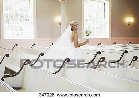 Bride holding wedding bouquet and walking down church aisle View Large Photo Image Stock Photograph - Bride holding wedding bouquet and walking down church aisle. Fotosearch