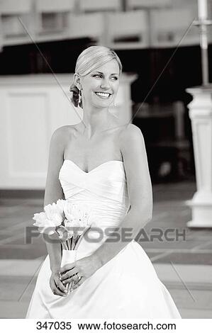 Bride holding wedding bouquet whilst standing at altar View Large Photo Image Stock Photography - Bride holding wedding bouquet whilst standing at altar. Fotosearch