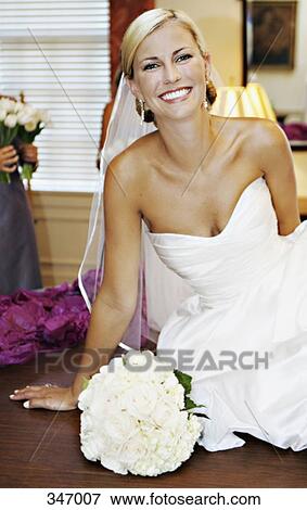 Bride leaning on wooden table next to wedding bouquet View Large Photo Image Stock Photo - Bride leaning on wooden table next to wedding bouquet. Fotosearch