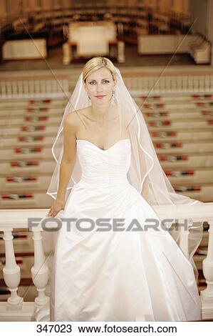 Stock Image - Bride sitting on railing in church stall. Fotosearch