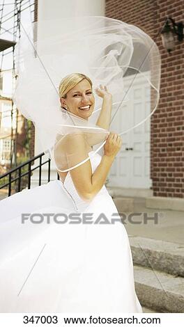 Bride standing on steps with veil blowing in the wind View Large Photo Image Stock Image - Bride standing on steps with veil blowing in the wind. Fotosearch
