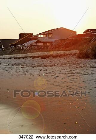 Stock Image - Sun setting over beach houses. Fotosearch