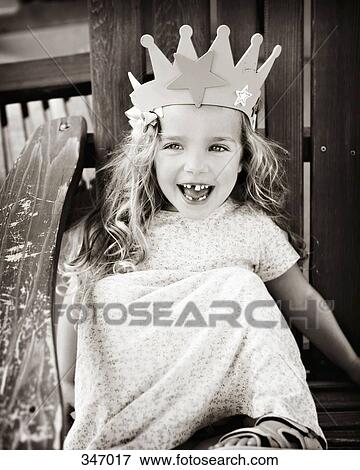 Young girl sitting in a wooden chair and wearing a crown View Large Photo Image Stock Photo - Young girl sitting in a wooden chair and wearing a crown. Fotosearch