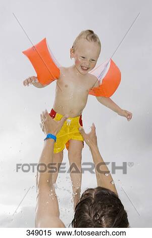 Stock Photography - Father throwing son into air from swimming pool. Fotosearch