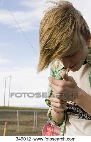 Stock Image - Young man igniting cigarette by the roadside. Fotosearch