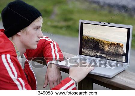 Young man using laptop outdoors View Large Photo Image Stock Image - Young man using laptop outdoors. Fotosearch