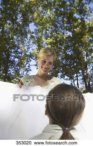 Mother hanging out laundry with daughter View Large Photo Image Stock Image - Mother hanging out laundry with daughter. Fotosearch