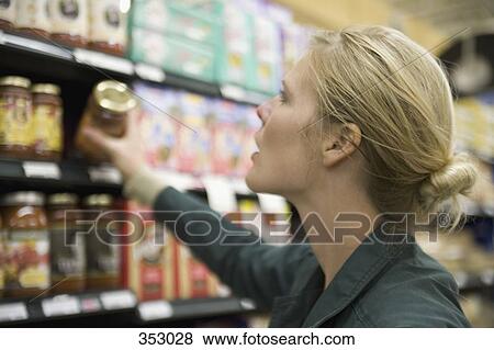 Woman choosing jar from supermarket shelf View Large Photo Image Stock Photo - Woman choosing jar from supermarket shelf. Fotosearch