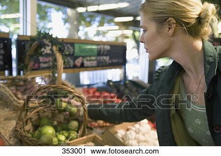 Stock Image - Woman choosing vegetables in supermarket. Fotosearch
