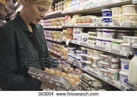 Picture - Woman in supermarket examining eggs. Fotosearch
