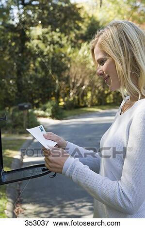 Stock Photo - Woman picking up the mail from the mailbox. Fotosearch